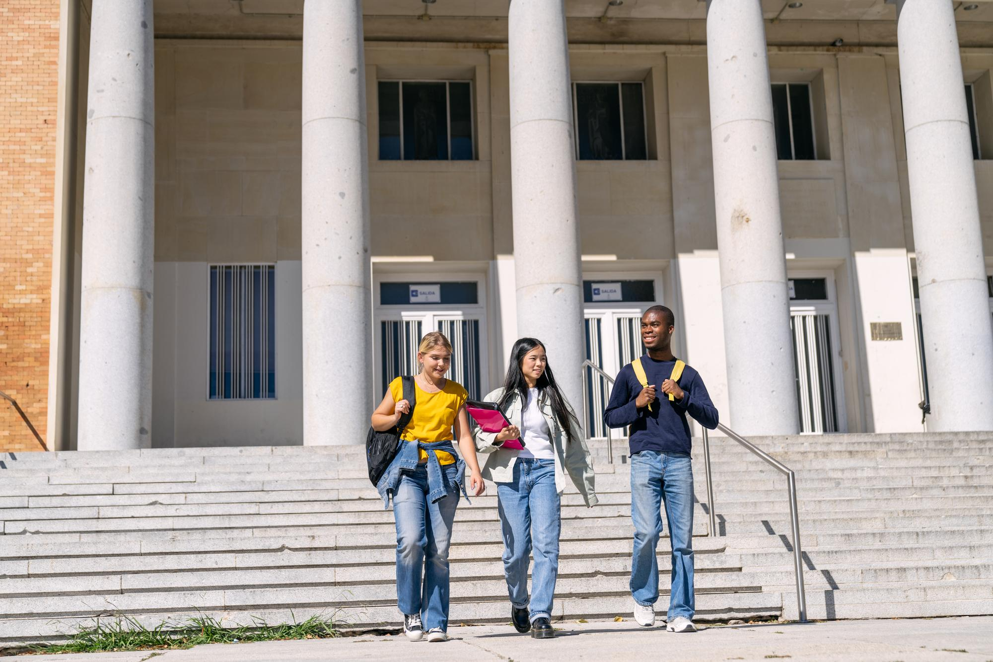 Students with backpacks walking down university campus stairs